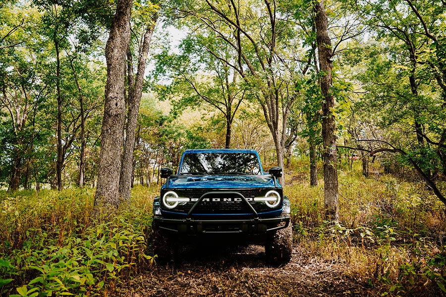 A dark blue Ford Bronco parked on an off-road trail