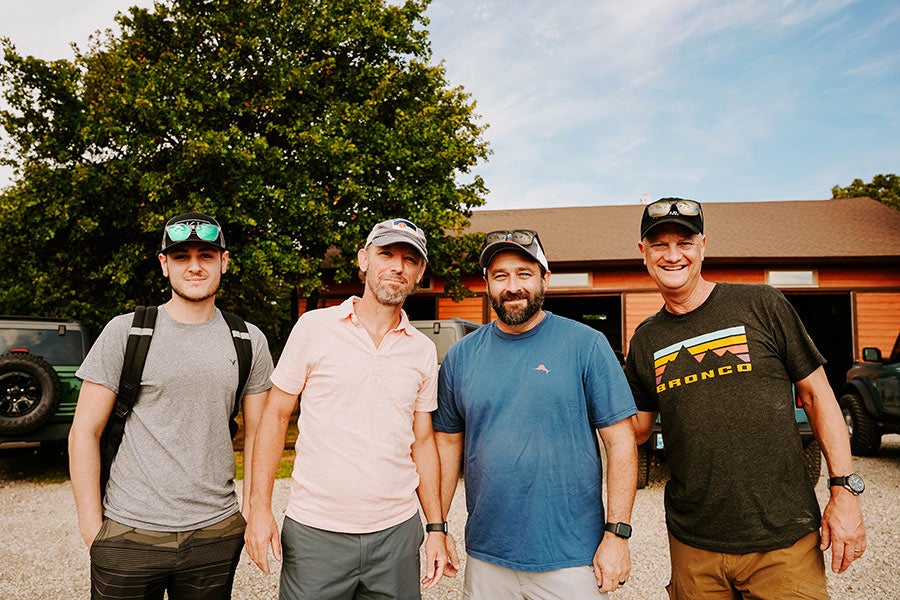 A group of four men posing for a photo outdoors.