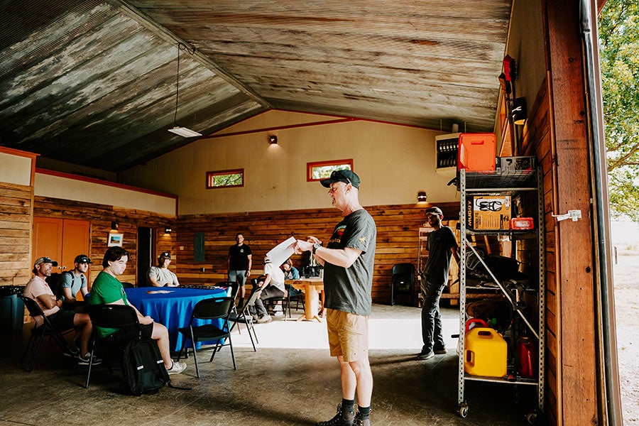 A group of people indoors looking at a mountain bike on a stand.