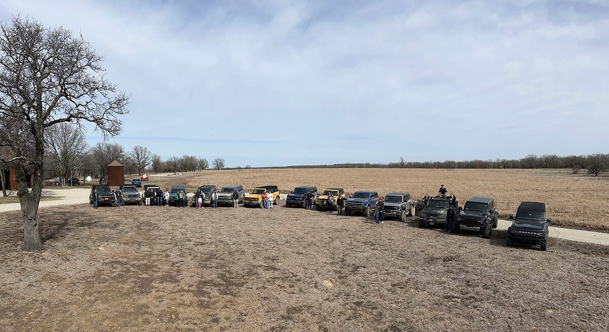 A wide view of a line of Ford Broncos parked in a rural field.
