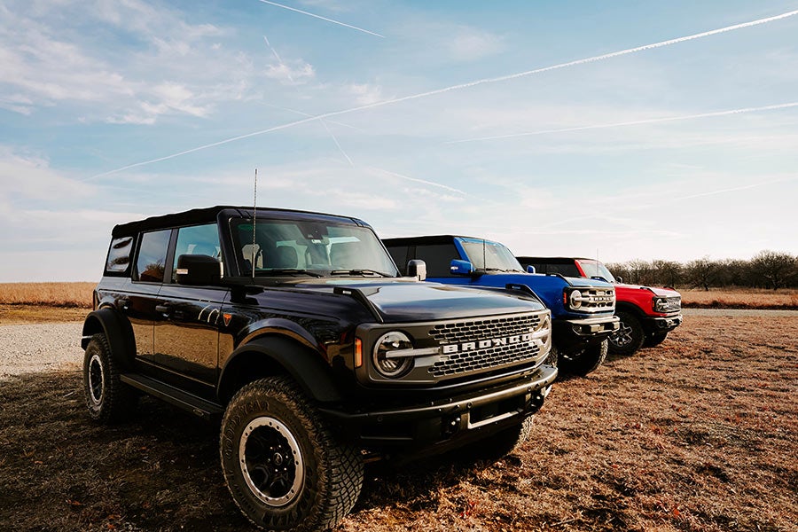 A line of Ford Broncos parked in a grassy field.