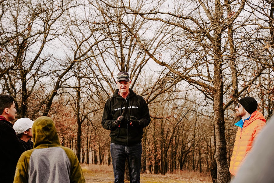 A man talking to a group of people next to a Ford Bronco.