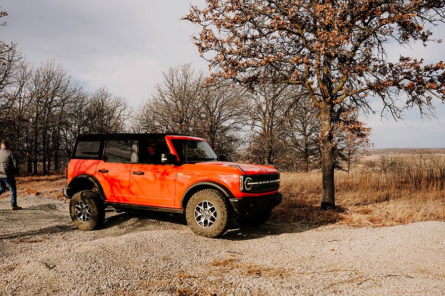 A side view of an orange Ford Bronco with black details.
