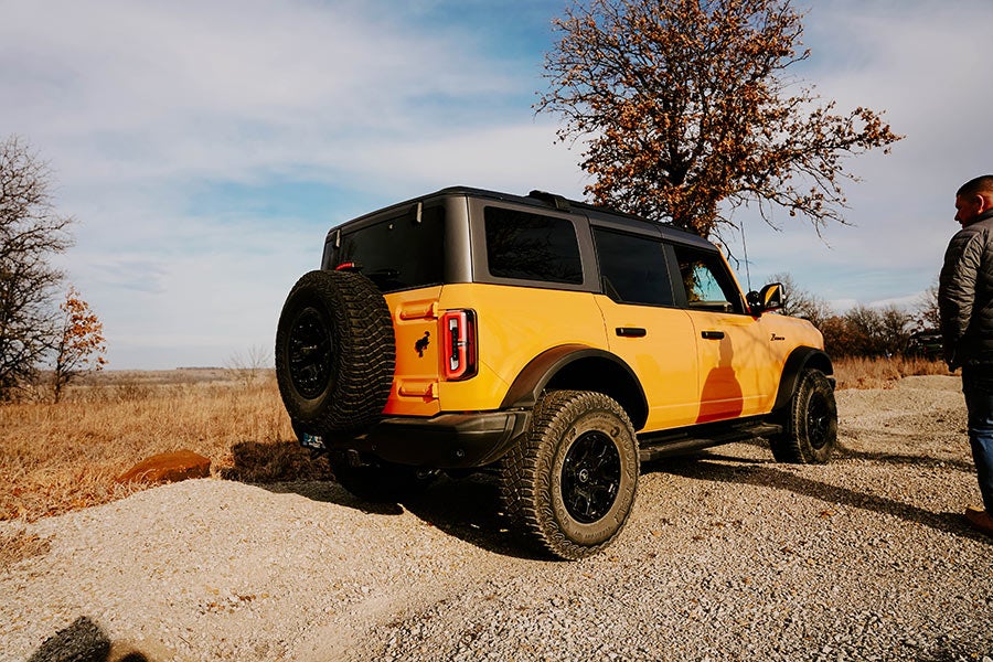 A rear view of a yellow Ford Bronco with its trunk open.