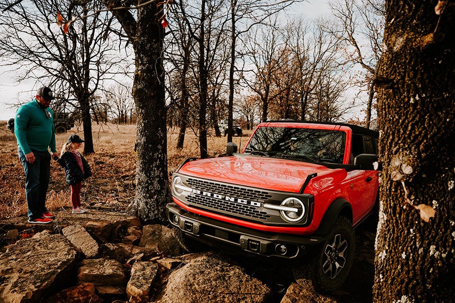 A side view of a red Ford Bronco off-roading.