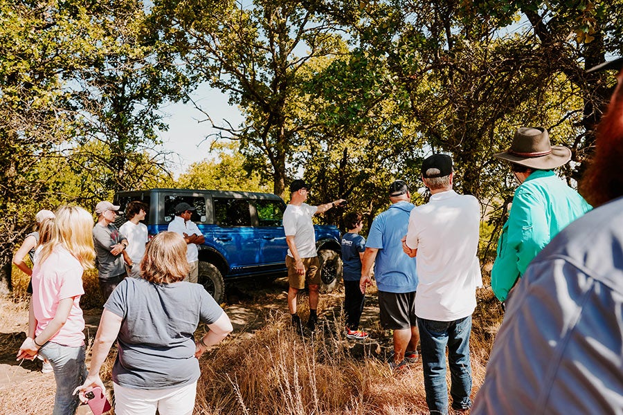 A person talking to another person next to a Ford Bronco.