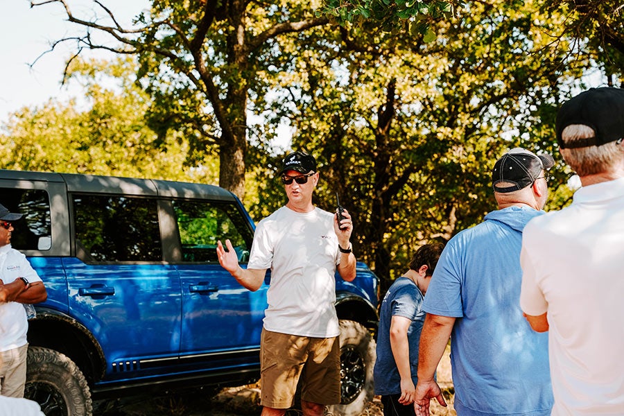 A family posing for a photo with a Ford Bronco in the background.