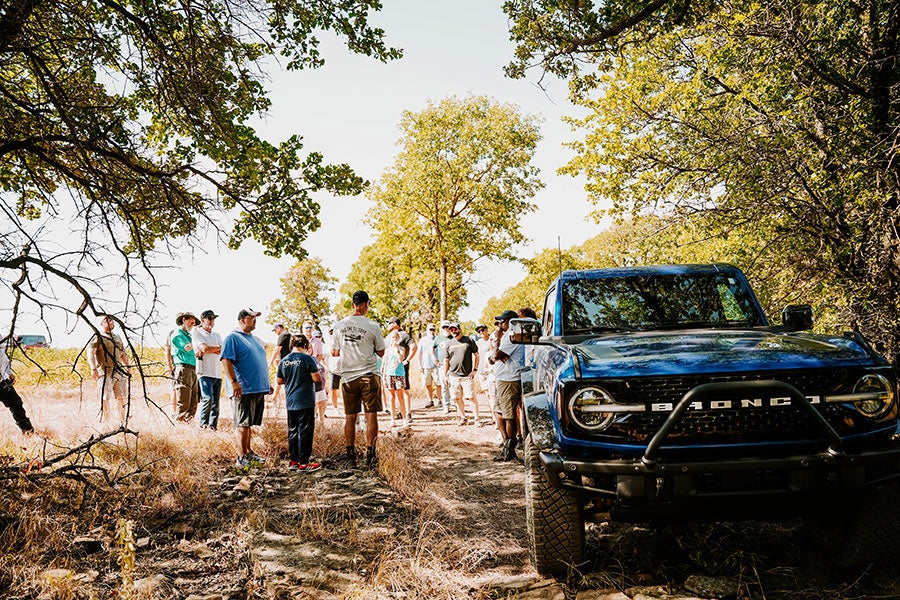 A side view of a green Ford Bronco off-roading.