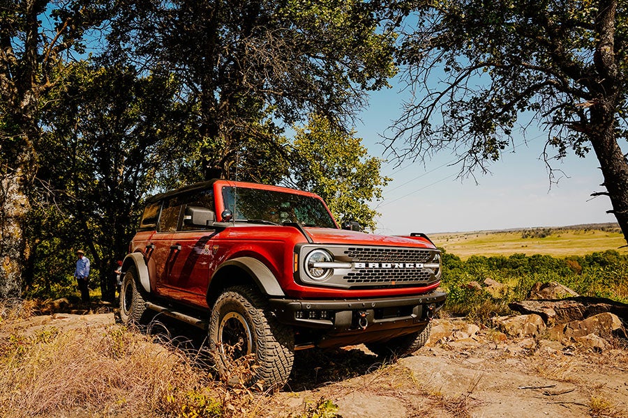 A low-angle front view of a blue Ford Bronco off-roading.
