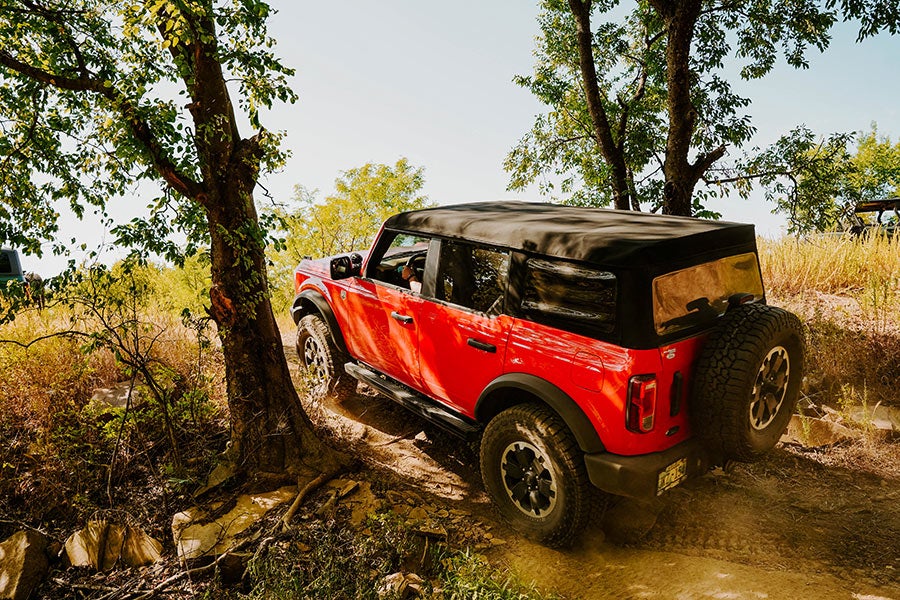 A rear view of a red Ford Bronco off-roading.