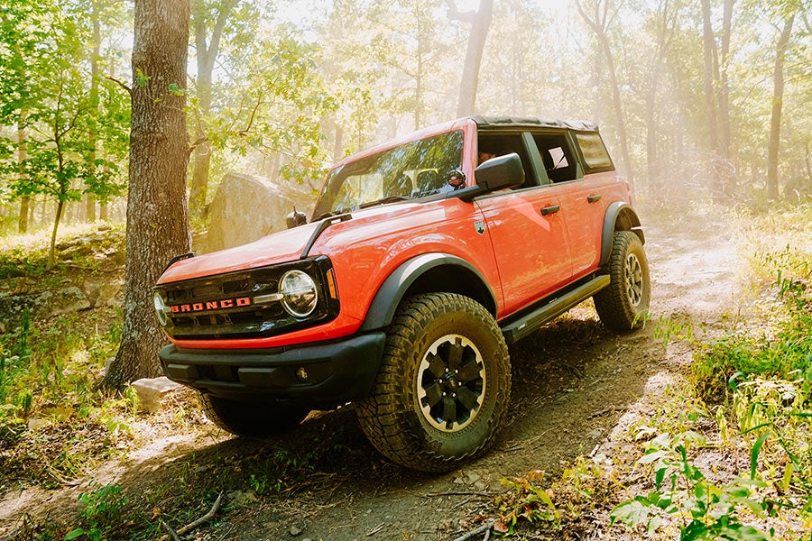 A side view of an orange Ford Bronco with its front tilted.