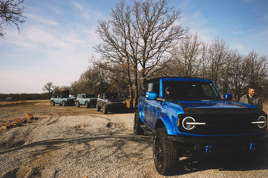 A convoy of off-road vehicles parked on a dirt path