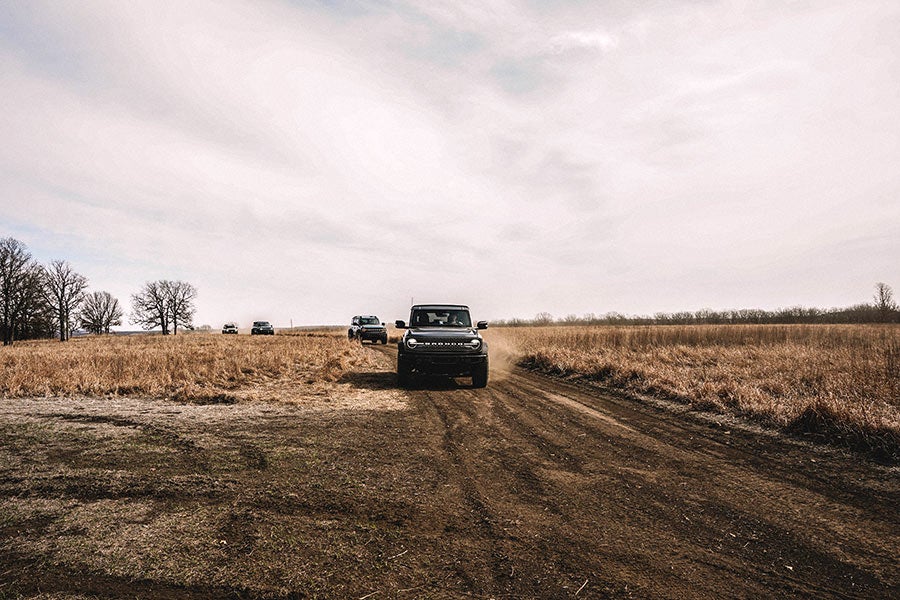 A side view of a gray Ford Bronco off-roading.