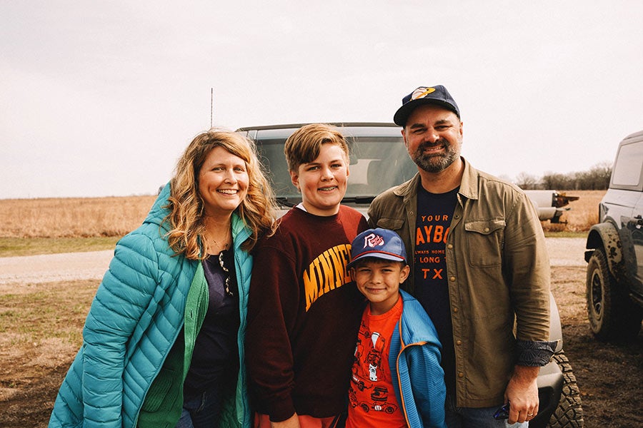 A family posing for a photo with a Ford Bronco in the background.