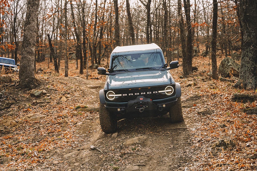 A front view of a blue Ford Bronco off-roading.
