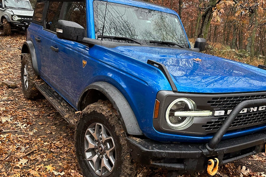 A blue Ford Bronco parked on a muddy off-road trail