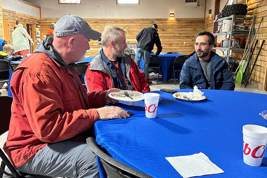 A group of people sitting at a blue table, eating and talking.