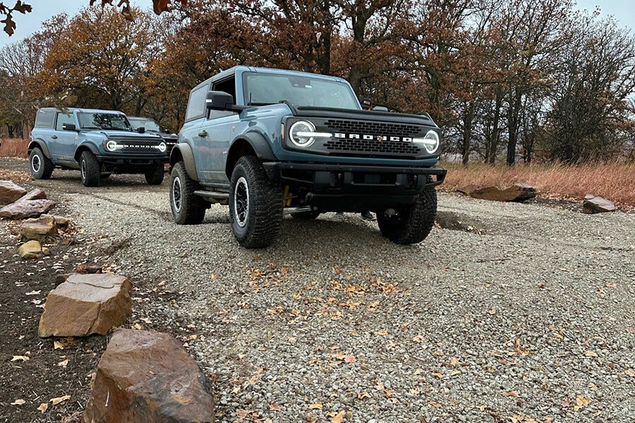  A black Ford Bronco parked on a dirt path with a group of people nearby.