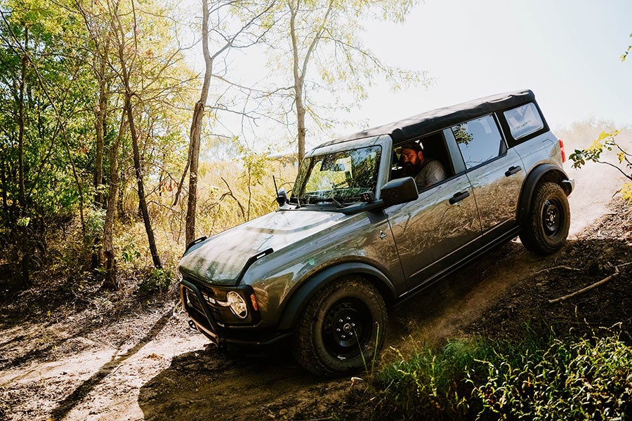 A tan Ford Bronco off-roading on a rocky trail.