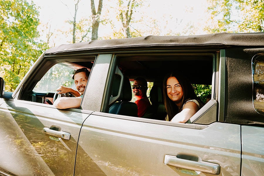 Two people smiling from the backseat of a Ford Bronco.