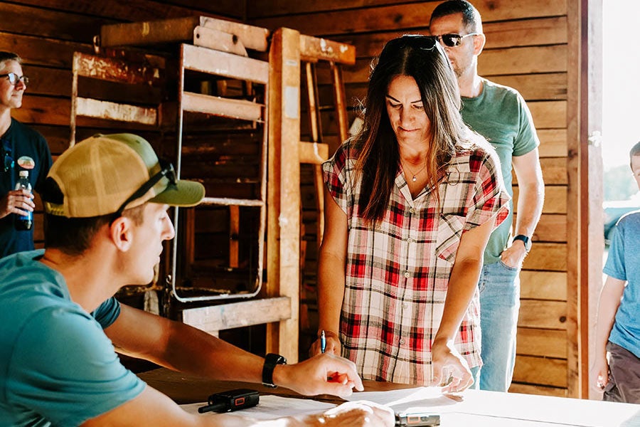 Two people looking at a laptop while sitting at a table.