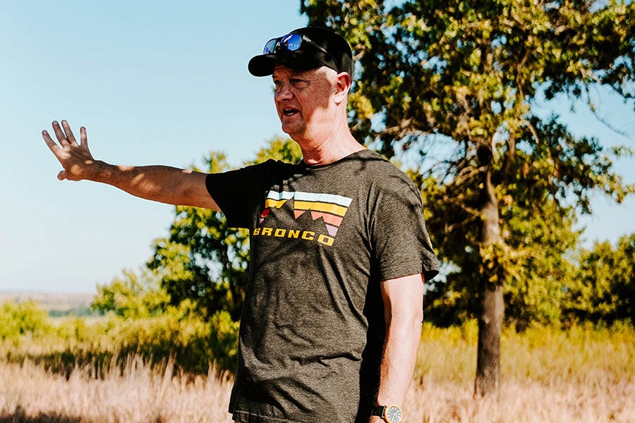 A man in a black t-shirt giving a hand signal.