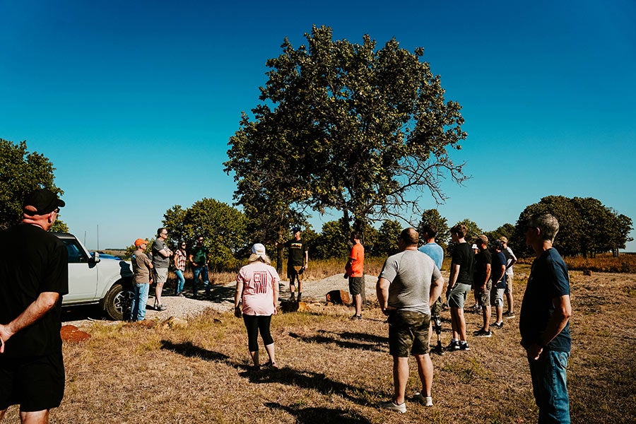 People standing in a field next to horses.