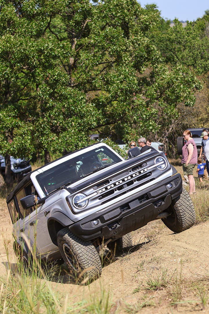 A front view of a white Ford Bronco tilted on a hill.