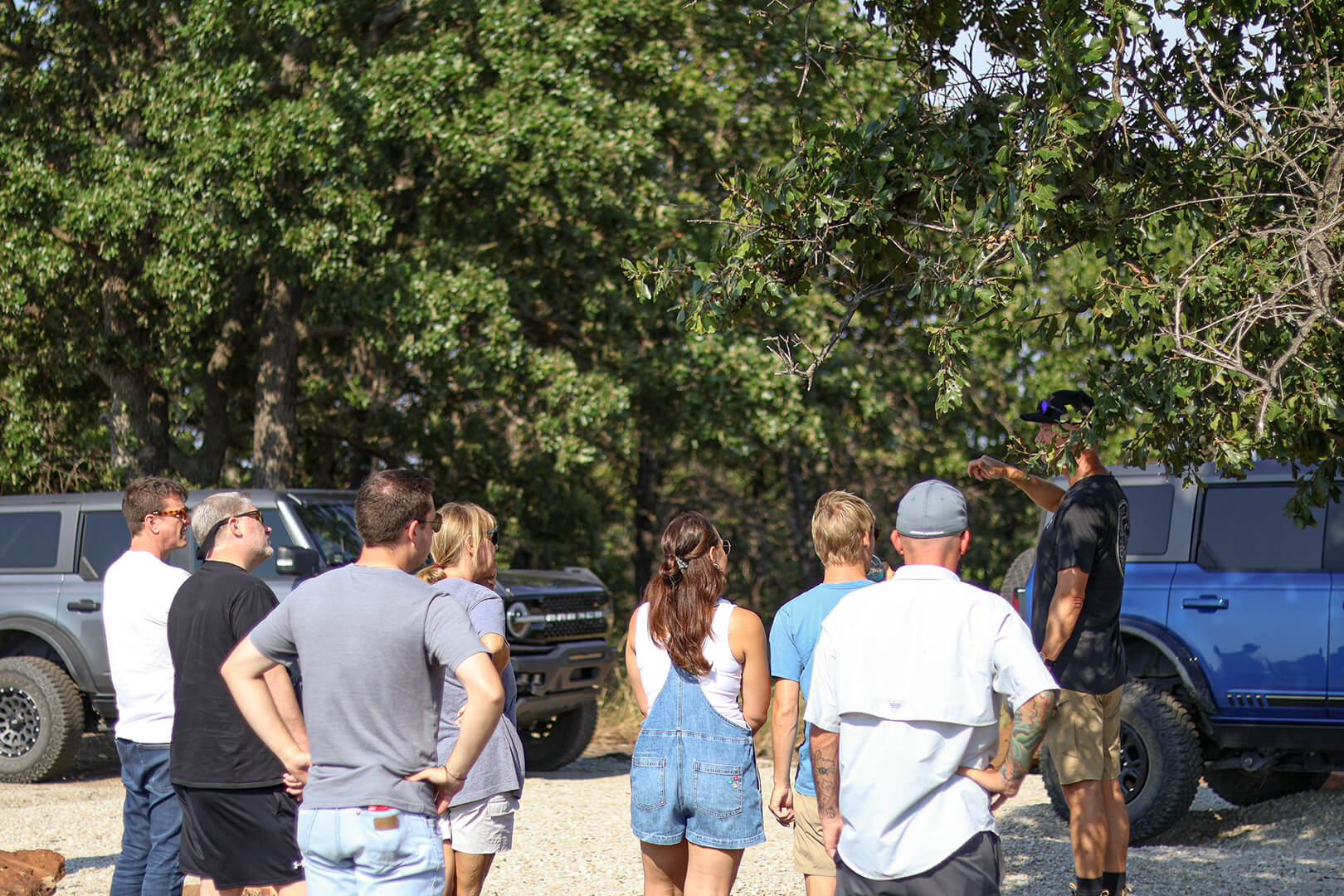 A group of people standing around a parked Ford Bronco.
