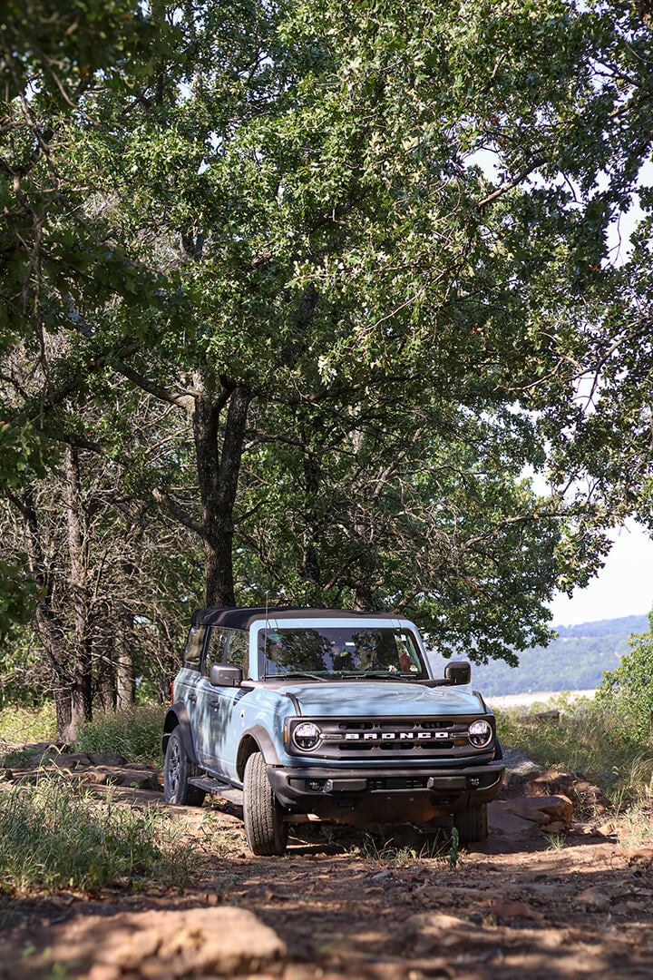 A side view of two Ford Broncos driving on a trail.
