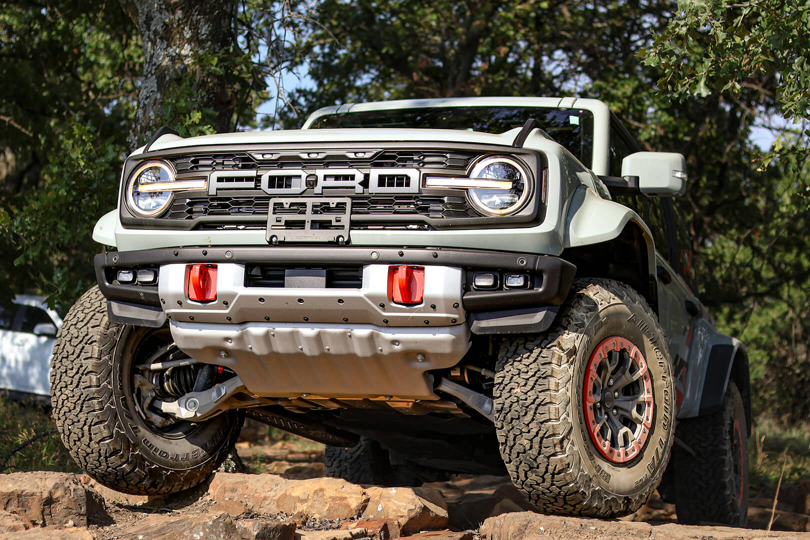 A low-angle front view of a green Ford Bronco with large tires.