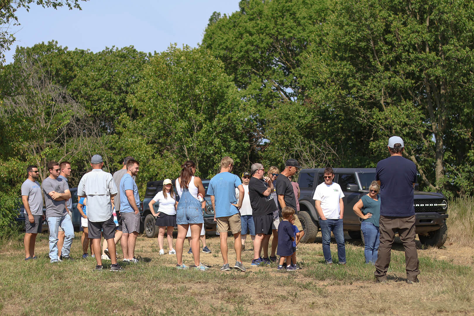 A group of people gathered around a Ford Bronco.