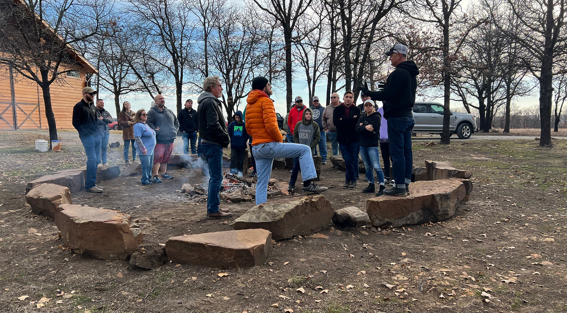 A group of people standing in a circle in a dry, grassy field