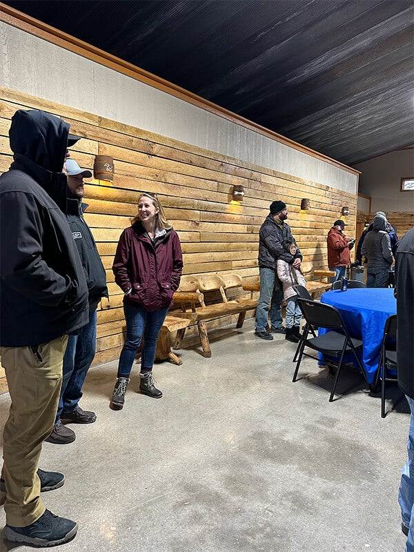 A group of people standing and talking in a rustic hall