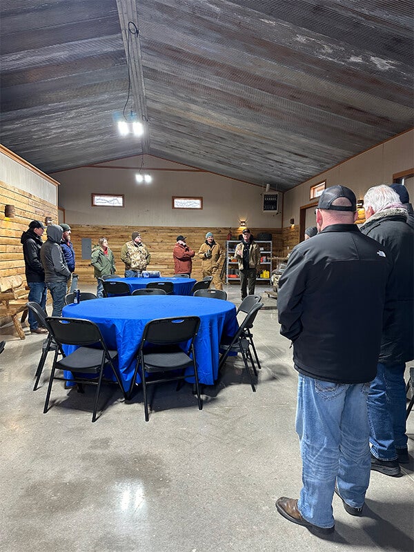 A group of people listening to a speaker in a rustic meeting hall