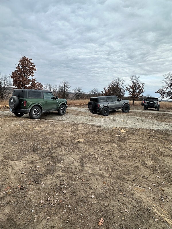 Three Ford Broncos parked on a gravel path in a rural area