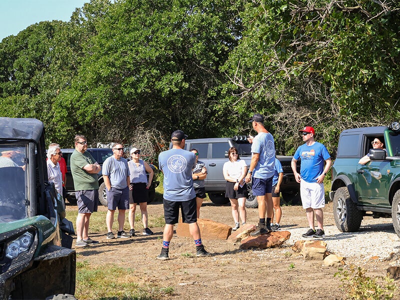 A group of people listening to a man speaking outdoors