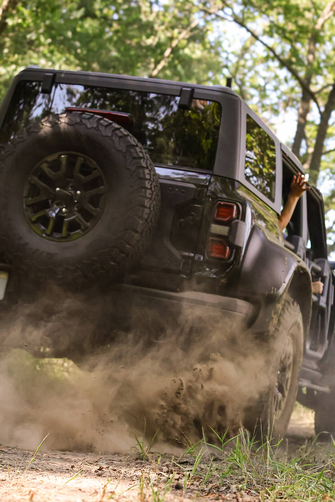 A close-up of a Ford Bronco's rear tire and suspension on a muddy track.