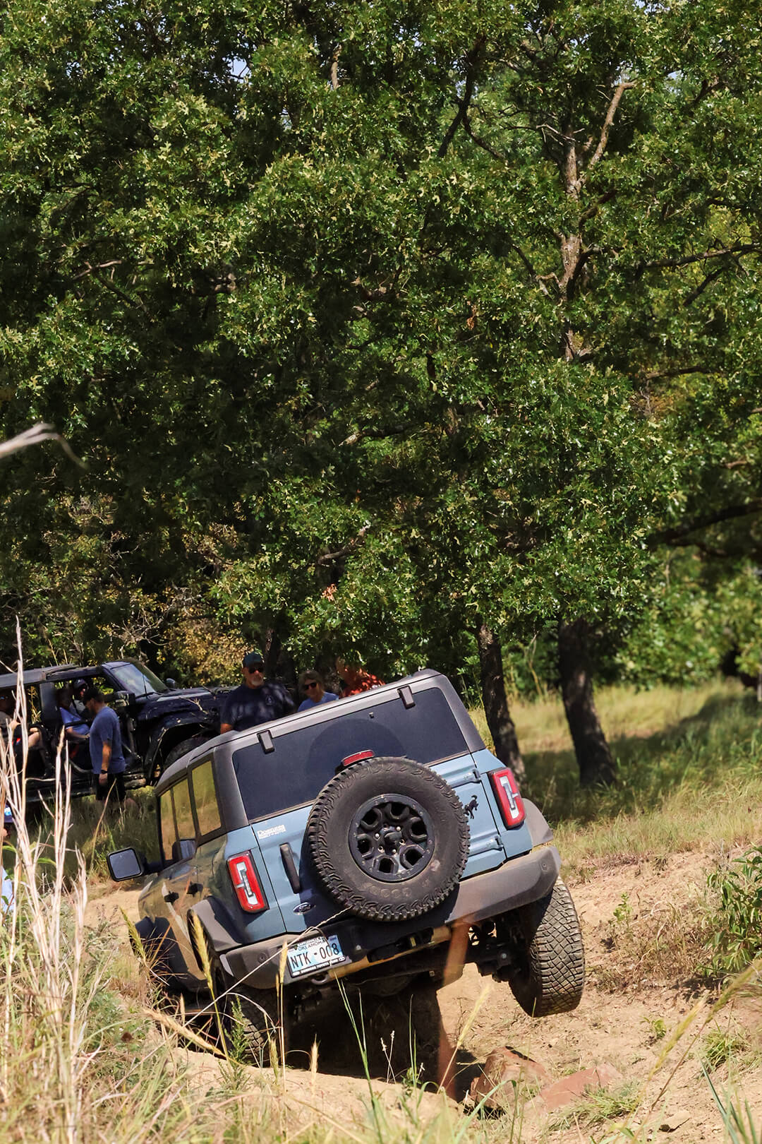 A close-up of a yellow Ford Bronco's front tire and bumper.