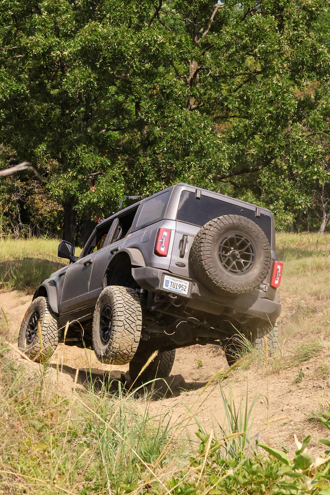 A side view of a Ford Bronco with a tilted front tire off-roading