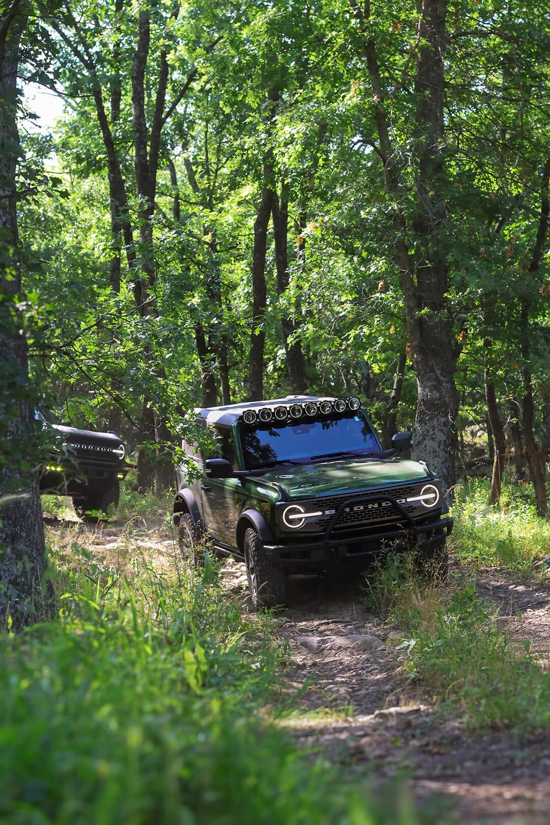 A front view of a dark Ford Bronco with a roof light bar.