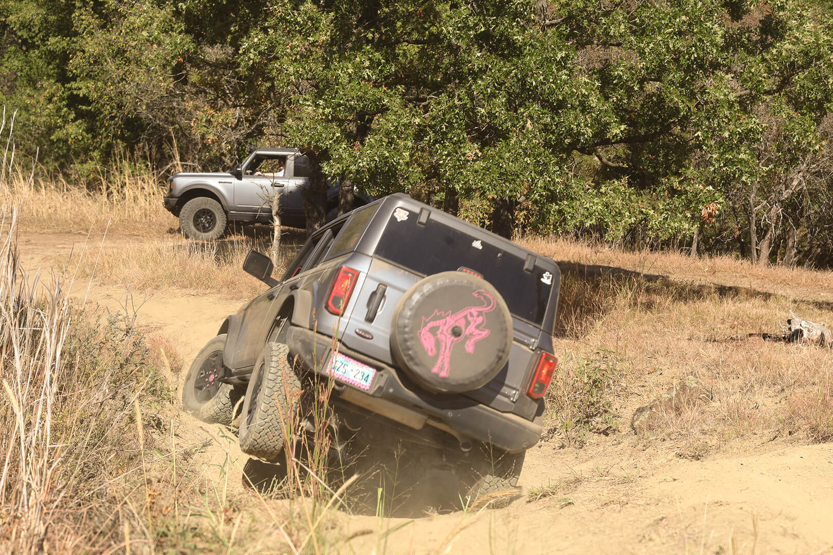 A front view of a red Ford Bronco tilted on a hill.