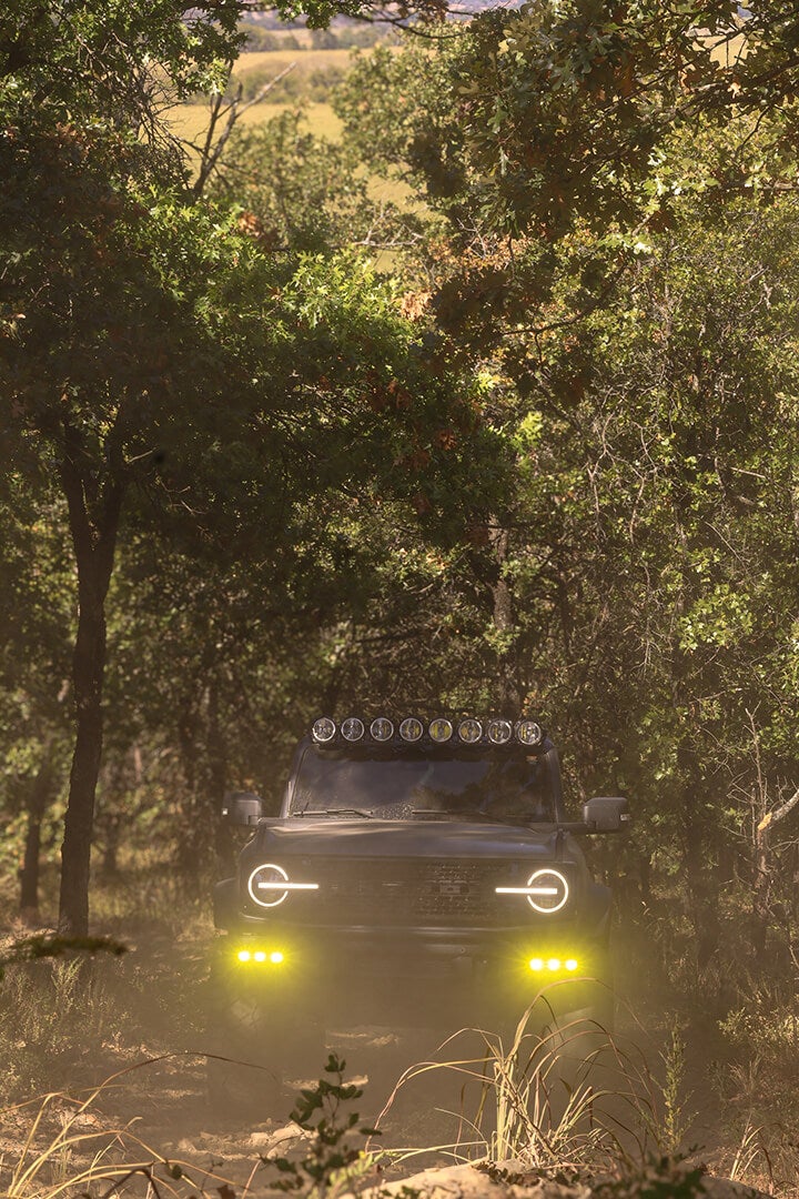 A front view of a black Ford Bronco with a roof light bar, off-roading.