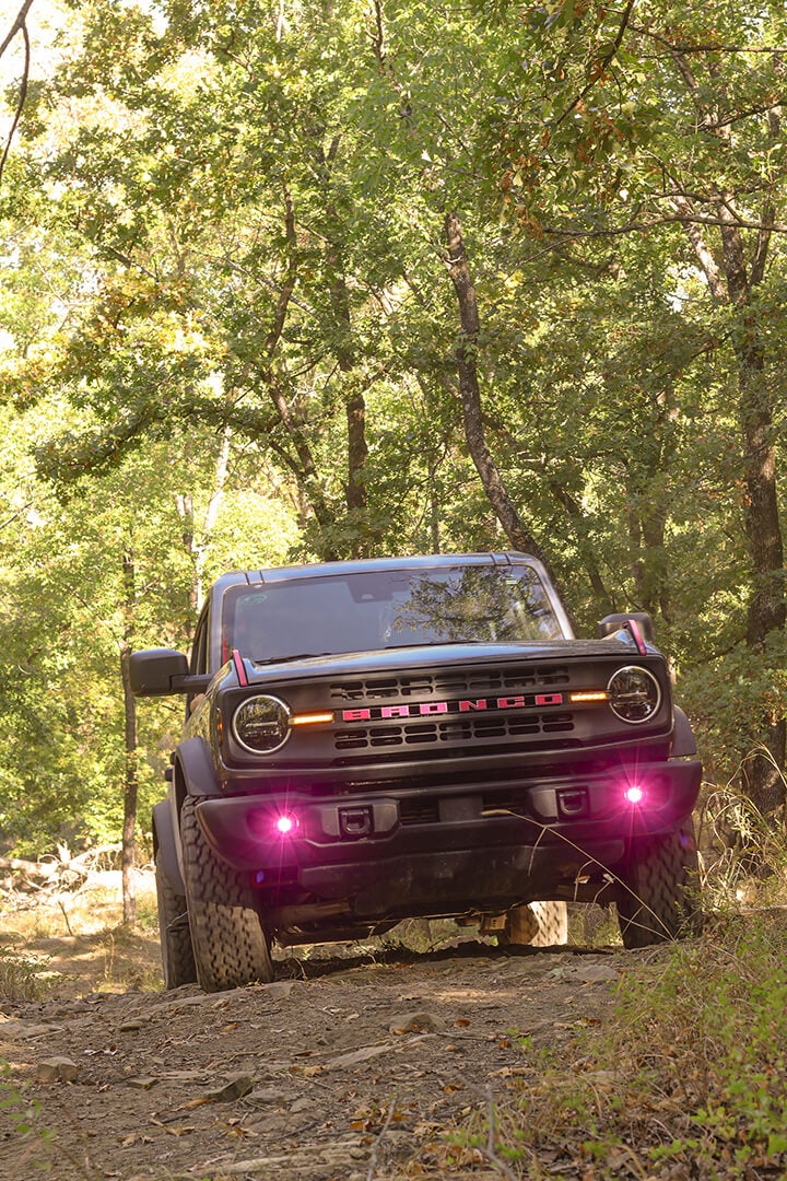 A front view of a black Ford Bronco at an angle with purple lights.